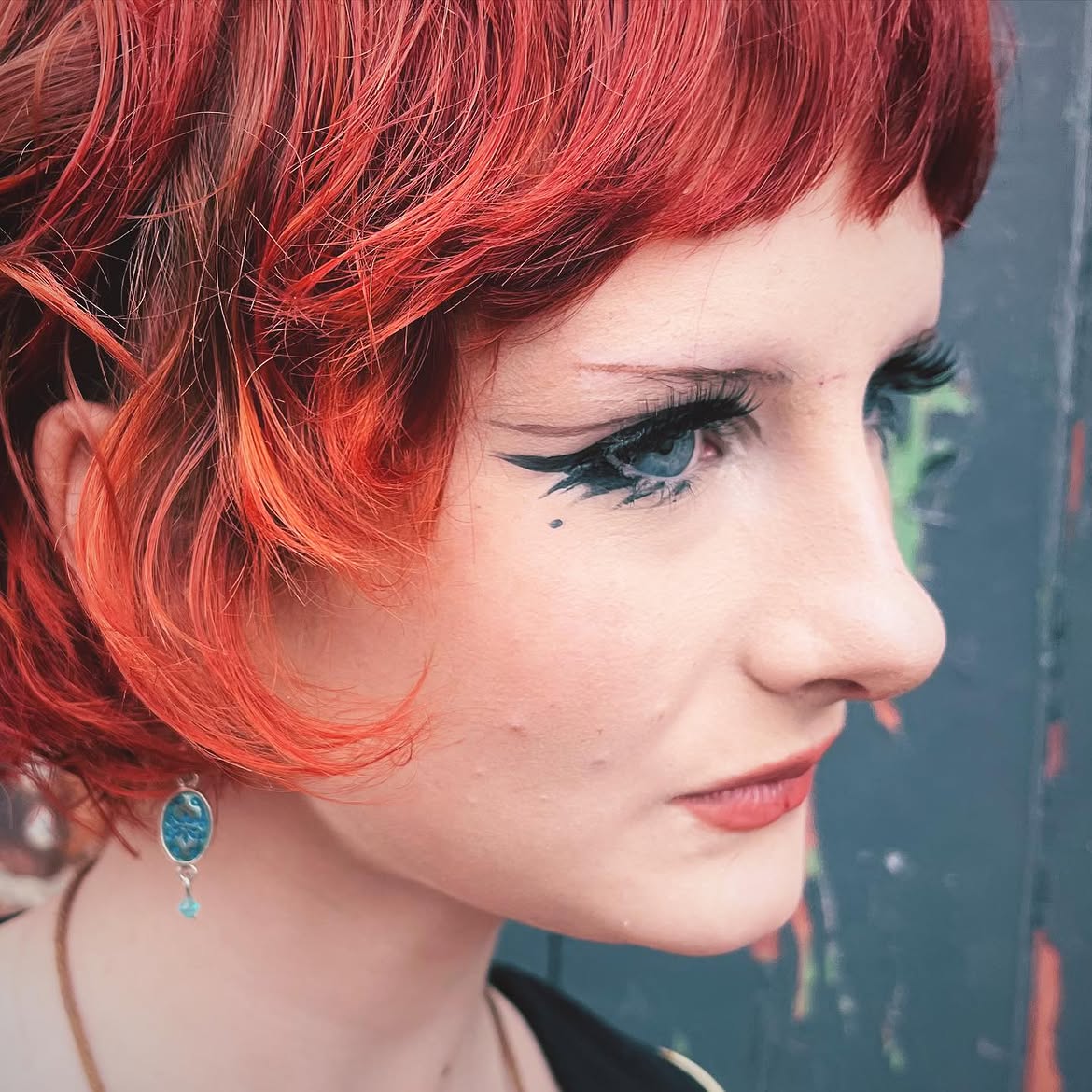 6. Fiery Red Curly Bob with Dramatic Winged Eyeliner